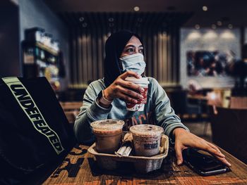 Portrait of young woman drinking coffee at restaurant