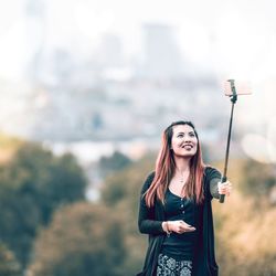 Portrait of smiling young woman standing against sky