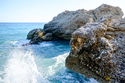 Rock formation in sea against clear sky