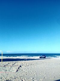 Scenic view of beach against clear blue sky