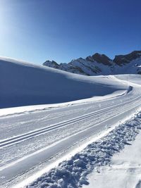 Scenic view of snow covered mountains against clear blue sky