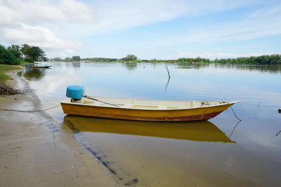 Boat moored in lake against sky