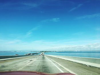 Road by sea against blue sky