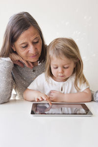 Grandmother with granddaughter using digital tablet