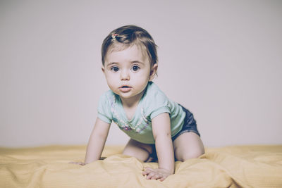 Portrait of cute baby girl on bed at home