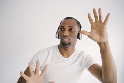 Man wearing headphones gesturing against white background