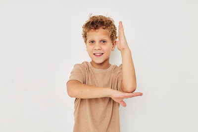 Portrait of cute boy standing against white background