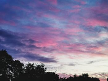 Low angle view of silhouette trees against dramatic sky