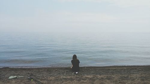 Rear view of woman relaxing at sandy beach