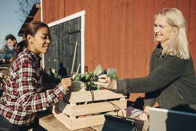 Mature woman paying female farmer through credit card at market