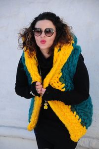 Portrait of a brunette girl in sunglasses, dressed in a warm, bright, long vest of large knitting