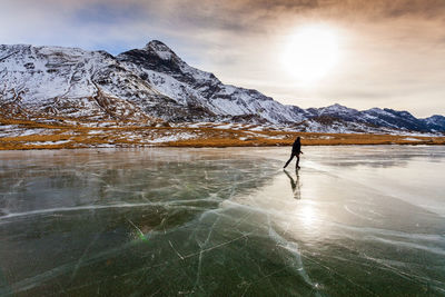 Person walking on snowcapped mountain against sky