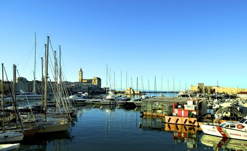 Boats moored at harbor against clear blue sky