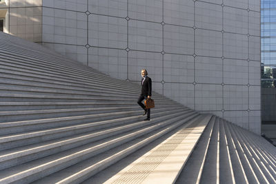 Businessman with bag moving up on steps