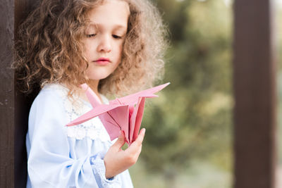 Cute girl looking at origami bird