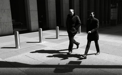 Men walking on sidewalk in city