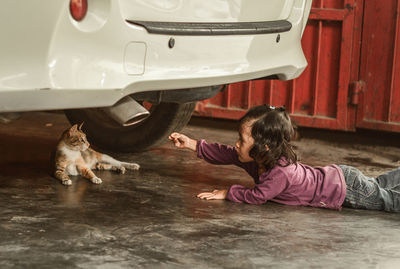 Side view of girl playing with kitten on street