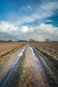 Road amidst field against sky