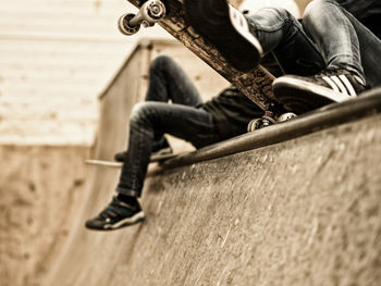 Low section of friends with skateboards sitting on sports ramp