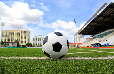 Soccer ball on field against buildings