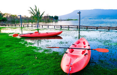 Red boat moored in lake against sky