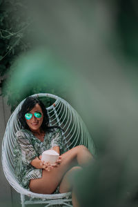 Portrait of woman wearing sunglasses sitting outdoors