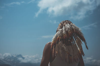 Rear view of man with headdress standing against blue sky