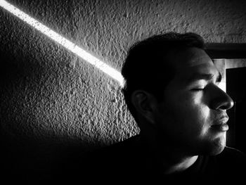 Portrait of young man looking away against wall