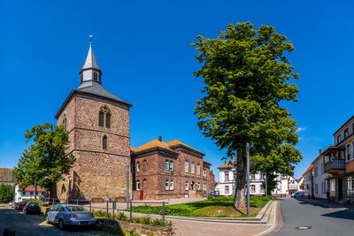 View of trees and buildings against blue sky