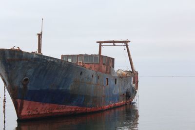 Abandoned ship in sea against clear sky