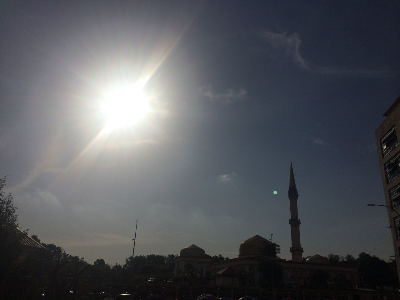 building exterior, architecture, built structure, sun, sky, sunbeam, sunlight, low angle view, lens flare, city, tower, church, religion, silhouette, blue, cloud - sky, outdoors, no people, day