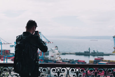 Rear view of man photographing against sea