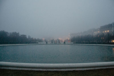 Scenic view of lake against sky in city