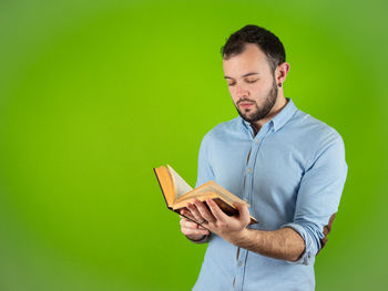 Man looking away while standing against green background