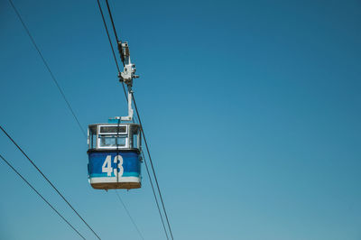 Low angle view of overhead cable car against blue sky