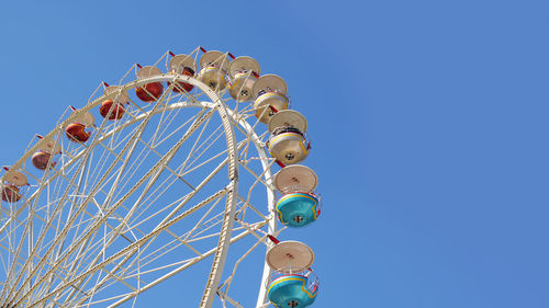 Low angle view of ferris wheel against clear blue sky