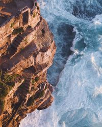 High angle view of man standing on cliff by sea