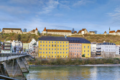 Buildings by river against sky