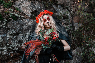 Closeup portrait of calavera catrina. young woman with sugar skull makeup and red flowers. dia 