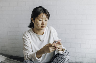 Girl is texting on a smartphone while sitting at home. copy space. teenage girl,  problematic skin