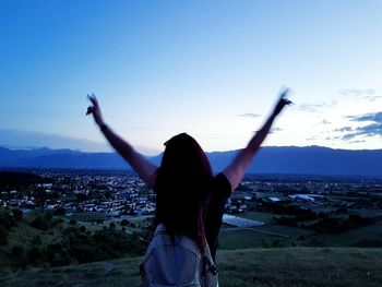 Rear view of woman standing against sky during sunset