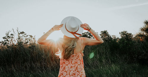 Midsection of woman standing by tree on field against sky