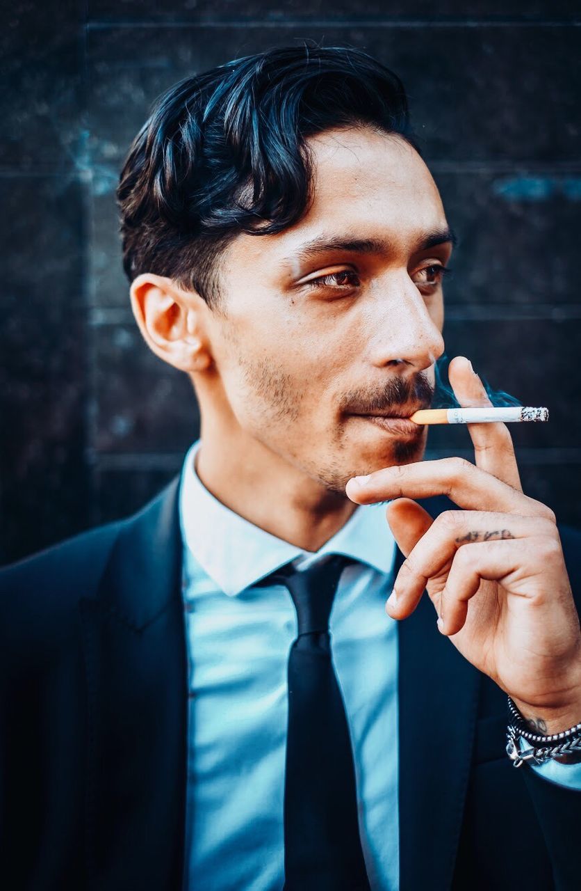 one person, young adult, communication, young men, front view, lifestyles, real people, portrait, headshot, bad habit, smoking - activity, activity, focus on foreground, smoking issues, beard, looking, cigarette, social issues, wireless technology