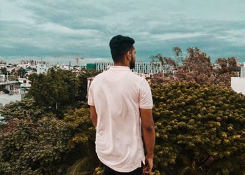 Rear view of man looking at city against sky