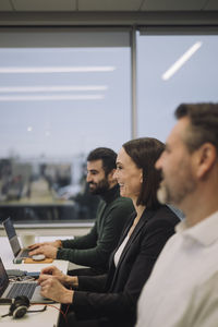 Happy businesswoman with colleagues discussing in meeting at work place