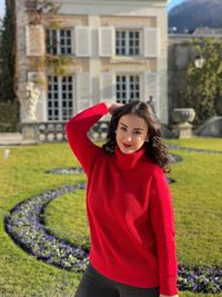 Portrait of young woman standing against building