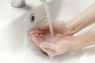 Close-up of person washing hands in sink