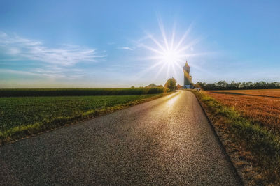 Road amidst field against sky