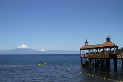 Gazebo on pier over sea against blue sky