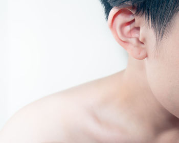 Close-up of shirtless boy against white background